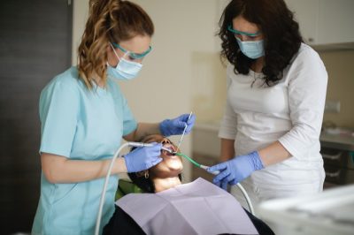 female-dentist-and hygienist-working-on-patient-post-COVID-