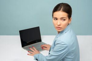 young woman at laptop looking back over shoulder