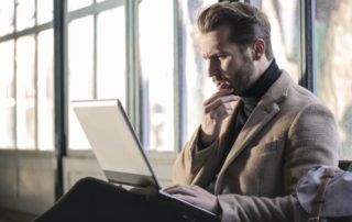 man-holding-chin-looking-at-laptop